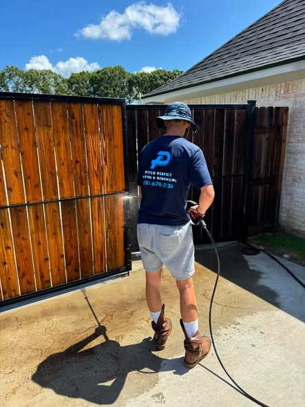 A crew member washing a wood fence.